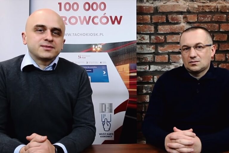 Dwaj mężczyźni siedzą przy stole w biurze.